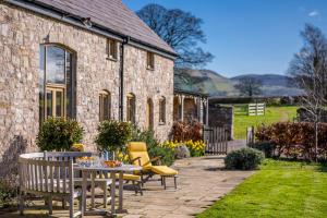 a patio with a table and chairs in front of a building at The-Longbarn in Ruthin