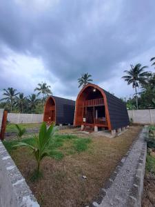 een bruin en zwart gebouw met palmbomen op de achtergrond bij Rinjani Koceng Bungalows in Tetebatu