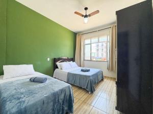 a bedroom with two beds and a green wall at Apto na beira da praia do Centro | ROMM109 in Rio das Ostras