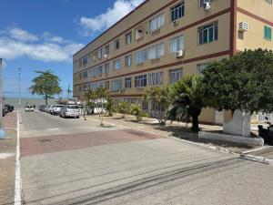 a building with cars parked on the side of a street at Apto na beira da praia do Centro | ROMM109 in Rio das Ostras