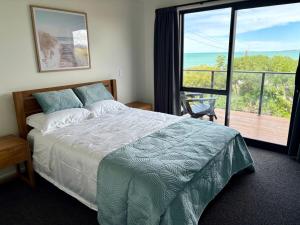 a bedroom with a bed with a view of the ocean at 45 degrees South in Kakanui