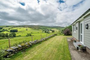 a farmhouse with a stone fence and green fields at Hendre-Llangwm in Llangwm