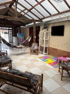 een woonkamer met een hangmat en een televisie bij Pousada Morada de Leste in Pontal do Paraná