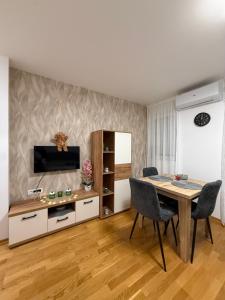 a dining room with a table and a tv at Apartmani Sirius in Čačak