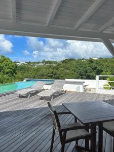 a deck with a table and chairs and a pool at Studio Terres Basses, Saint-Martin in Les Terres Basses