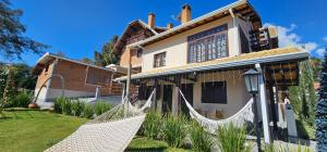 a house with two hammocks in front of it at Pousada Flor de Lua Monte Verde in Monte Verde