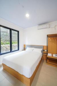 een slaapkamer met een groot wit bed en twee ramen bij Naava Village in Tagalbato +30 foto's