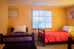two beds in a room with yellow walls and a window at Hostal Turpial Patagonia in Puerto Natales