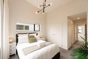 ein Schlafzimmer mit einem großen weißen Bett und einem Kronleuchter in der Unterkunft Modern 4-Bedroom Home in Silverdale in Silverdale