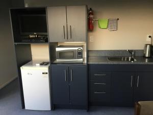 a small kitchen with a microwave and a sink at South Catlins Cottage in Tokanui