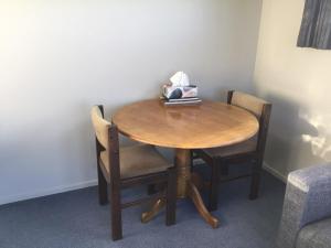 a wooden table with chairs and a box of tissues at South Catlins Cottage in Tokanui