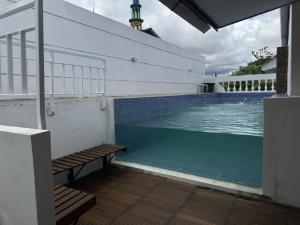 a swimming pool with benches next to a house at Omah Putih Jogja in Yogyakarta