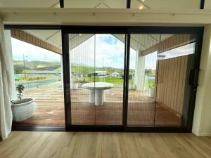 eine große Glastür in einem Zimmer mit Terrasse in der Unterkunft Light-Filled Coastal Hideaway in Raglan + 41 Fotos