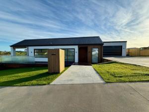 ein Haus mit schwarzem Dach und etwas Gras in der Unterkunft Light-Filled Coastal Hideaway in Raglan