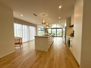 eine große Küche mit Holzböden und einem großen Fenster in der Unterkunft Light-Filled Coastal Hideaway in Raglan