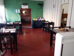 a dining room with tables and chairs and a green wall at Hotel Lincoln in Villa Gesell
