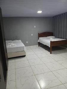 1 Schlafzimmer mit 2 Betten und Fliesenboden in der Unterkunft Kitnet na mata atlantica in Ubatuba