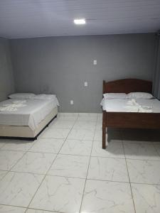 zwei Betten in einem Zimmer mit Fliesenboden in der Unterkunft Kitnet na mata atlantica in Ubatuba