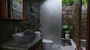 a bathroom with a stone sink and a toilet at Sanis House in Penginyahan +27 photos