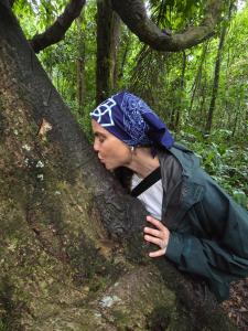 een vrouw die tegen een boom in het bos leunt bij capybara tours and lodge in San Pedro
