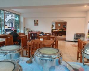 a restaurant with tables and chairs and a man sitting at a table at Erawan in in Mae Sot