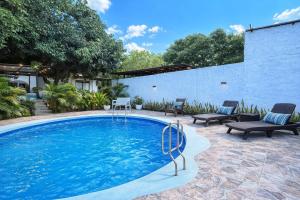 a large swimming pool with two chairs and a patio at Villa Tranquila - Paraíso Privado con Piscina y Amplios Espacios Naturales con Casa Campestre in Ricaurte