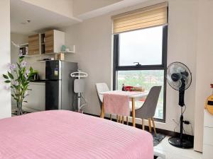ein Schlafzimmer mit einem rosa Bett und einem Tisch und einem Fenster in der Unterkunft Nuvali Sta Rosa Laguna in Pulong Cacawate