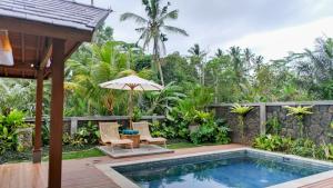 an outdoor pool with two chairs and an umbrella at Sanis House in Penginyahan