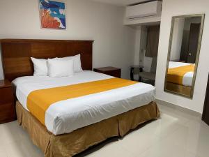 a bedroom with a large bed with yellow and white sheets at Hotel Frontera Baja in Mexicali +29 photos