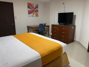 a bedroom with a bed and a desk and a television at Hotel Frontera Baja in Mexicali