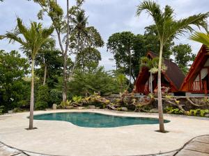 a swimming pool in front of a house with palm trees at Dalung Tropical in Dalung