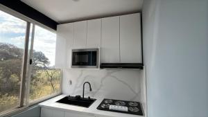 a white kitchen with a sink and a microwave at Cuarto Privado in Arandas