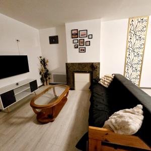 ein Wohnzimmer mit einem schwarzen Sofa und einem Kamin in der Unterkunft Apparemment Mawen in Tarbes