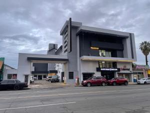 a building with cars parked in a parking lot at Hotel Frontera Baja in Mexicali