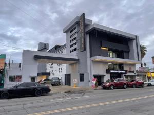 a building with cars parked in front of it at Hotel Frontera Baja in Mexicali