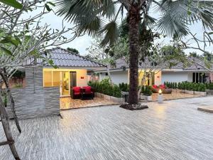 a house with a palm tree in a courtyard at All Times Pool Villas in Ban Tha Khun