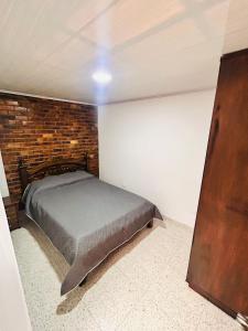 a bedroom with a bed and a brick wall at Casa Nobsa ArteSana in Nobsa