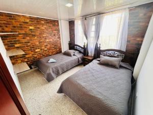 a bedroom with two beds and a brick wall at Casa Nobsa ArteSana in Nobsa