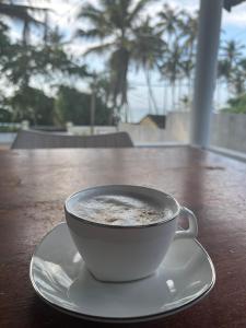 a cup of coffee on a plate on a table at Rella Dream in Matara