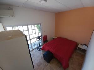 a bedroom with a red bed and a window at Departamento LA PALMERA ARGENTINA in San Luis