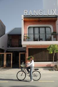 a woman riding a bike in front of a building at Ranglux Homestay Phan Rang in Phan Rang–Tháp Chàm