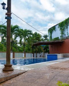 a swimming pool with a building and palm trees at Yorhanys Hotel in Puerto Barrios