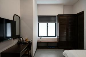 a bedroom with a window and a desk and a television at Ranglux Homestay Phan Rang in Phan Rang–Tháp Chàm