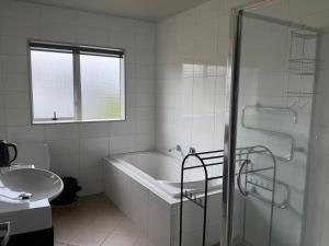 een witte badkamer met een bad en een wastafel bij Sunny garden view suite with private bathroom in Auckland