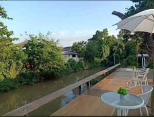 a wooden deck with tables and an umbrella next to a river at River Bend Villas in Mae Rim +9 photos