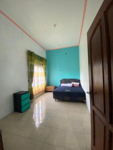 a bedroom with a bed and a blue wall at Homestay loteng in Madasari