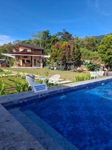 a swimming pool with chairs and a house at Juma cottages in Tuktuk Siadong