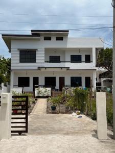 a white house with a fence in front of it at Sea La Vie Guesthouse in Pooc