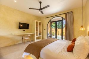 een slaapkamer met een bed, een bureau en een tv bij Terracota Villas in Kuta Lombok +43 foto's