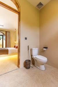 een badkamer met een toilet in een kamer met een bed bij Terracota Villas in Kuta Lombok